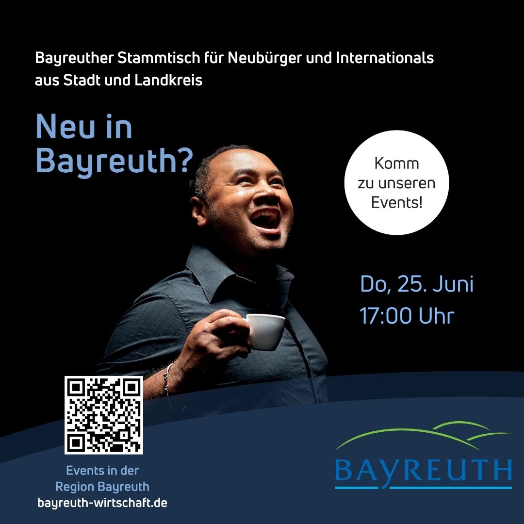 Hinweis auf dem Stammtisch "Neu in Bayreuth". Zusehen ist ein fröhlicher Mensch mit Kaffeetasse vor schwarzem Bühnenhintergrund